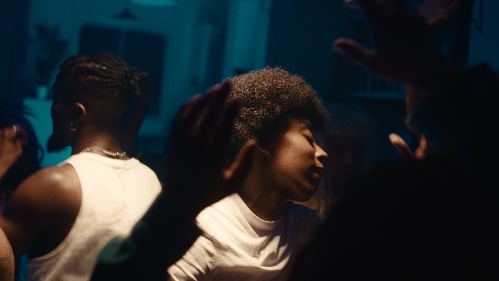 Two dancers moving through a crowded, blue-toned room