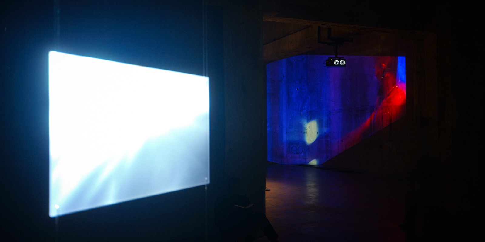 Projected films filling the dark concrete gallery space at Tate Modern