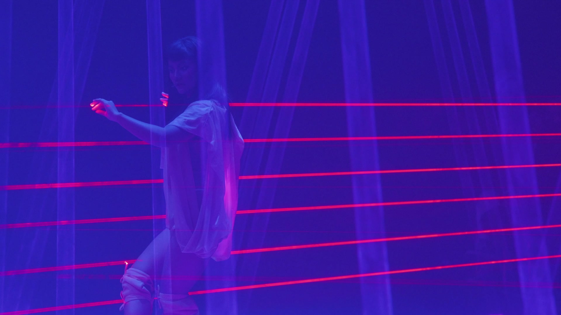 Close view of a performer reaching between bright red laser lines