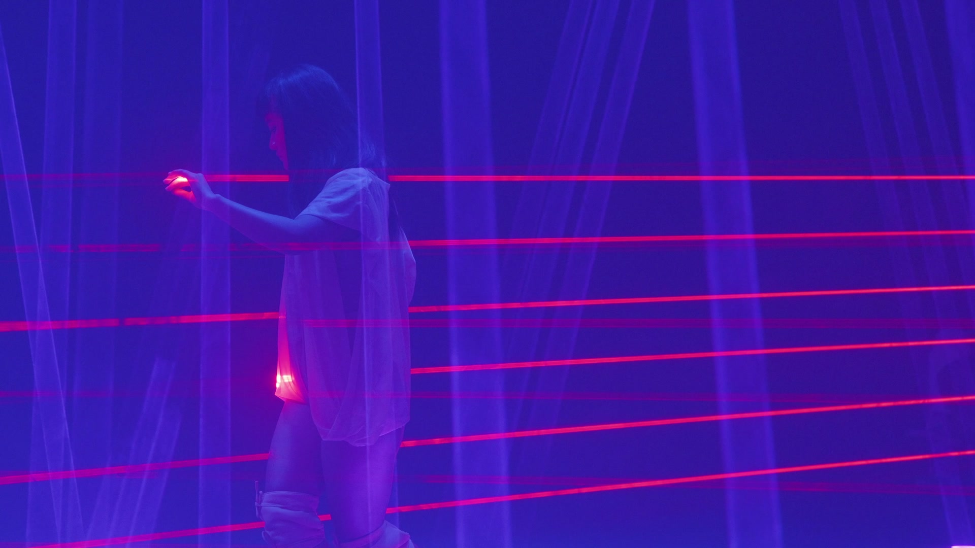 Performer reaching through a field of horizontal red laser lines